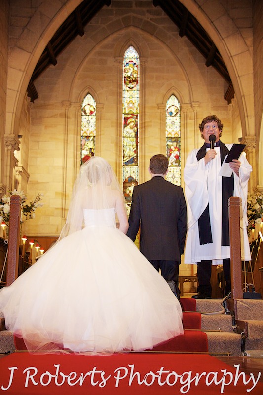 Bride and groom kneeling for prayers at St Thomas' North Sydney - wedding photography sydney